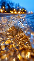 Macro shot of water splash with golden bokeh lights at dusk, crystalline droplets creating natural wave formation against blurred city lights background.