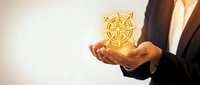 Businessman holding glowing golden compass symbol in cupped hands representing guidance, direction, navigation and strategic business leadership concepts.