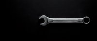 Chrome combination wrench tool isolated on black background for automotive repair and mechanical work projects.