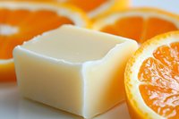 Fresh orange slices next to natural soap bar on white background, showcasing organic skincare ingredients and aromatherapy elements for spa and wellness products.