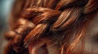 Close-up of auburn braided hair showing intricate texture and weaving pattern against soft blurred background. Perfect for beauty and hairstyling content.