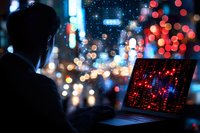 Man working on laptop with stock market data at night, illuminated by colorful city lights and bokeh. Dark silhouette against urban background creates dramatic atmosphere.