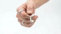 Hand holding silver key with wedding ring on finger against white background isolated for security and real estate concepts.