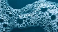 Abstract blue foam bubbles texture with organic flowing patterns and circular formations for modern design backgrounds.