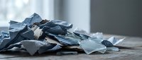 Broken glass fragments scattered on floor after accident or vandalism creating dangerous sharp debris mess requiring careful cleanup and safety precautions.