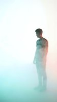 Young man standing in profile with blurred, ethereal effect transitioning from cool teal to warm coral tones. Suitable for mental health, psychology, and wellness concepts.