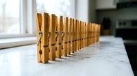 Row of wooden clothespins lined up on white marble counter near kitchen window creating organized laundry preparation display for household cleaning tasks.