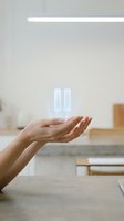 Hands holding glowing pause symbol in modern kitchen representing break, rest, mindfulness and work-life balance in daily routine.
