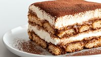 Layered tiramisu cake slice with mascarpone cream and cocoa powder dusting on white plate, classic Italian dessert for cafes and restaurants.