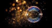 Magical soap bubble with rainbow reflections floating among golden bokeh lights and sparkling particles on dark background for fantasy designs.