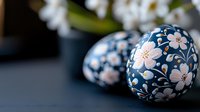 Decorative Easter egg with delicate pink floral pattern on deep blue background, traditional folk art style painting with soft bokeh effect and selective focus.