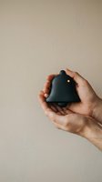 Hands gently holding small black house model with warm light, symbolizing home ownership, real estate investment, and property protection on neutral background.