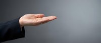 Caucasian male hand in business suit making open palm gesture against neutral gray background, suitable for concepts of offering, support, protection, and professional communication.