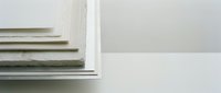 Stack of white and beige books on clean shelf against minimalist wall background for modern interior design and educational concepts.