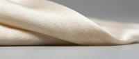 Soft beige fabric with natural texture and gentle folds creating elegant drapery against neutral background for textile and fashion design projects.