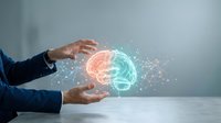 Businessman in formal attire holding glowing digital brain with orange and turquoise hemispheres, representing artificial intelligence, innovation, and technology solutions for business applications.