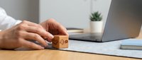 Businessman hand placing wooden cube with customer service icons on desk next to laptop in modern office workspace for feedback concept.