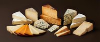 Assorted gourmet cheese selection with blue cheese, aged cheddar, brie and artisan varieties arranged on dark background for culinary photography.
