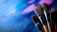 Professional art brushes arranged against vibrant blue and purple textured acrylic paint background, showcasing creative tools for artists and painters.