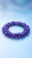 Purple flower wreath made of small delicate blooms arranged in circular shape on soft blue background for spring decoration and floral design projects.