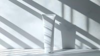 White cosmetic tube on minimal white background with dramatic window shadow stripes creating modern composition for beauty product presentation.