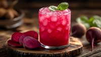 Fresh beetroot juice cocktail with ice cubes and mint garnish on wooden board. Healthy detox drink with vibrant red color for wellness and nutrition concepts.