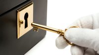 Hand in white glove inserting golden key into brass keyhole lock plate on dark surface for security and access concept.