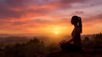 Young woman meditating in lotus pose during golden hour sunset with dramatic orange and pink sky clouds creating peaceful spiritual atmosphere for wellness.