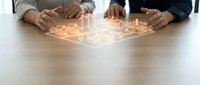 Business professionals protecting digital real estate icons with hands over glowing property symbols on wooden table representing investment security.