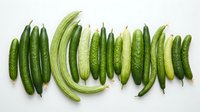 Fresh green cucumbers arranged in rows on white background, suitable for food photography, recipe blogs, grocery marketing, and healthy eating content.