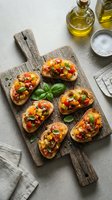 Toasted bread slices topped with diced tomatoes, garlic, and fresh basil leaves arranged on rustic wooden board with olive oil and salt for appetizers or bruschetta recipes.