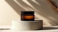 Amber glass cosmetic jar on white podium with palm leaf shadow overlay creating minimal luxury composition for skincare product photography.