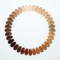 Foundation makeup samples arranged in circular pattern showing diverse skin tone shades from light to dark for inclusive beauty and cosmetic matching.