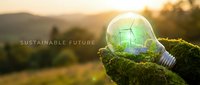 Green energy concept with wind turbine inside glowing light bulb held by hands covered in moss against sunset landscape for environmental sustainability.