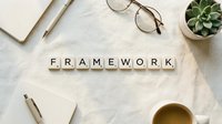 Business framework concept with wooden letter tiles on white desk surrounded by office supplies, glasses, succulent plant and coffee cup for strategic planning.