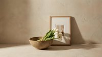 Minimalist home decor with wooden bowl, white tulips and framed artwork on neutral beige wall. Modern interior design styling for contemporary living spaces.