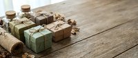 Handmade soap bars wrapped in kraft paper and twine arranged on rustic wooden surface with burlap fabric for natural skincare, wellness and eco-friendly product packaging.
