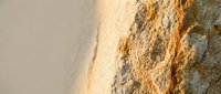 Golden sand texture with natural rock formation creating warm earth tones and organic patterns for backgrounds and natural design elements.