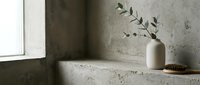 Minimalist concrete windowsill with white ceramic vase holding dried greenery branches and natural light creating soft shadows for home decor and interior design projects.