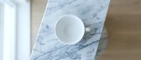 White ceramic bowl on blue marble surface with wooden floor, overhead view for kitchen and home decor design.