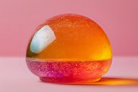 Colorful layered sphere with orange and pink gradient on pink background shows liquid density experiment with dramatic lighting and reflective surface.