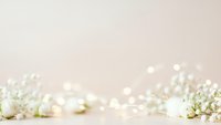 Delicate white baby's breath flowers with soft bokeh lights on neutral beige background creating romantic wedding or celebration atmosphere.