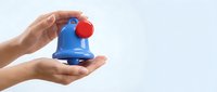 Caucasian female hands holding a bright blue notification bell with red button on light background, symbolizing alerts and reminders.
