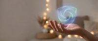 Hand holding glowing holographic spiral energy orb with swirling blue and green light effects in modern interior with warm ambient lighting for futuristic concepts.