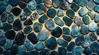 Textured blue stone mosaic wall with irregular rounded shapes and golden grout lines creating an organic pattern. Natural rock surface with contrasting colors.