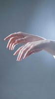 Elegant female hands with silver rings in graceful gesture against soft gray background for beauty and skincare concepts.