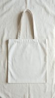 Blank white cotton tote bag with long handles displayed flat on neutral linen background, ready for custom printing, branding, or design projects.