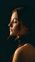 Young woman in profile with closed eyes enjoying warm golden light against dark background for wellness and mindfulness concepts.