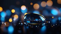 Large water drop on dark surface reflects blue and golden bokeh lights creating magical macro photography composition with shallow depth of field.