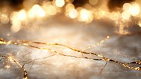 Delicate golden cracks on marble texture with glowing bokeh lights and sparkles create luxurious abstract background for elegant design projects.